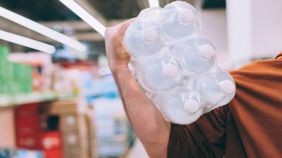UE ogłosiła plan ochrony ludności w razie najgorszego scenariusza. Na zdjęciu mężczyzna w supermarkecie niosący zgrzewkę wody na ramieniu
