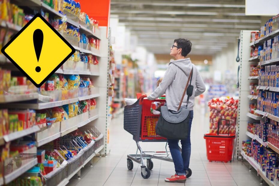 Pilne wycofanie chipsów Lay's. Na zdjęciu kobieta z wózkiem sklepowym w alejce supermarketu patrzy na półki.