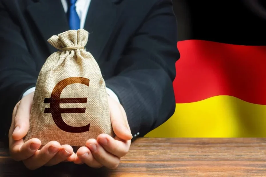 Niemieccy miliarderzy się mnożą. Zdjęcie: mężczyzna z workiem euro na tle niemieckiej flagi